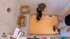 man and child tamping down shower pan for walk-in shower