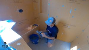 man holding mud scraper inside of incomplete walk-in shower