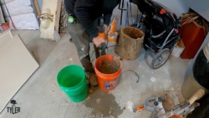 man standing in front of two buckets of water