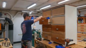 man installing cherrywood drawer front to dresser