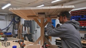 man drilling additional dowel hole into support piece of tabletop